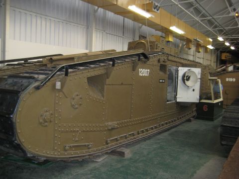 1966 Jeep CJ5 - A tan tank, marked with the number 12007, is displayed indoors, with another vehicle visible in the background.