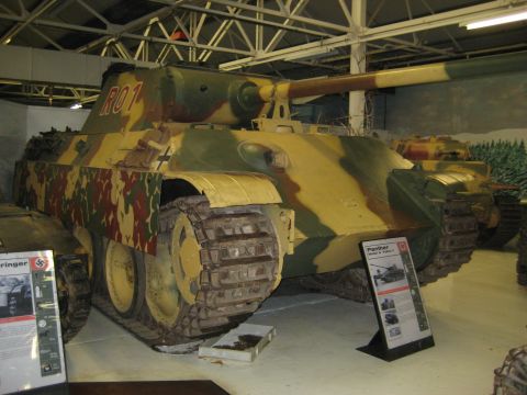 1966 Jeep CJ5 - A Panther tank is displayed indoors with informational signs nearby.