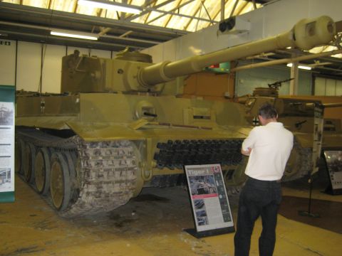 1966 Jeep CJ5 - A man examines a large tank on display in a museum, with informational signs nearby.