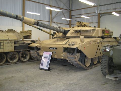 1966 Jeep CJ5 - A military tank is displayed indoors next to another vehicle, with signage indicating it is from The Tank Museum.