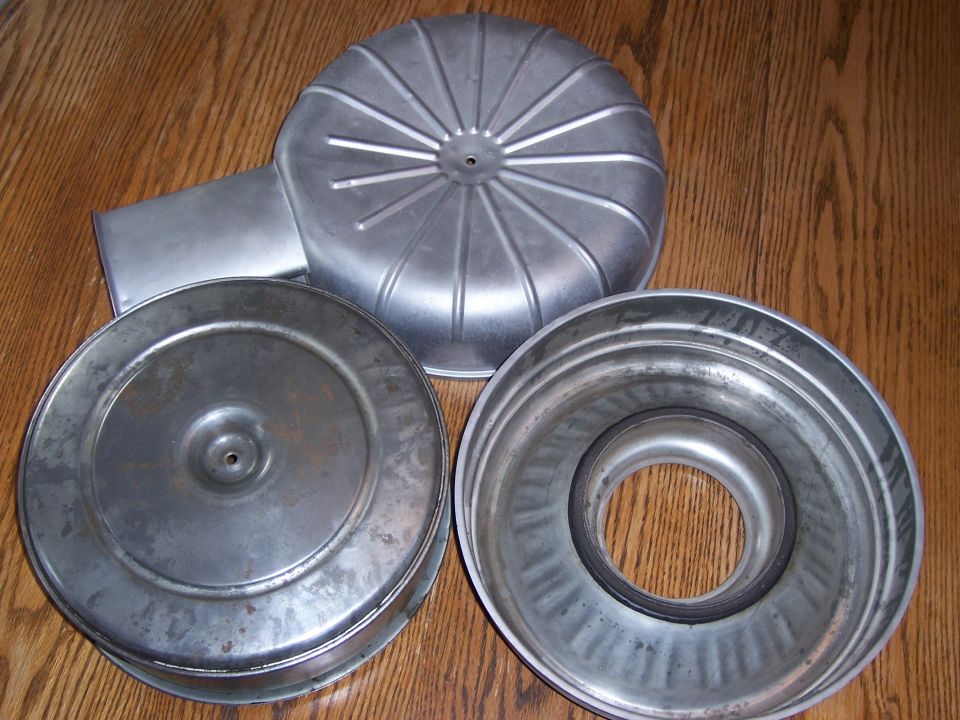 Disassembled round metal air cleaner housing pieces on a wooden table