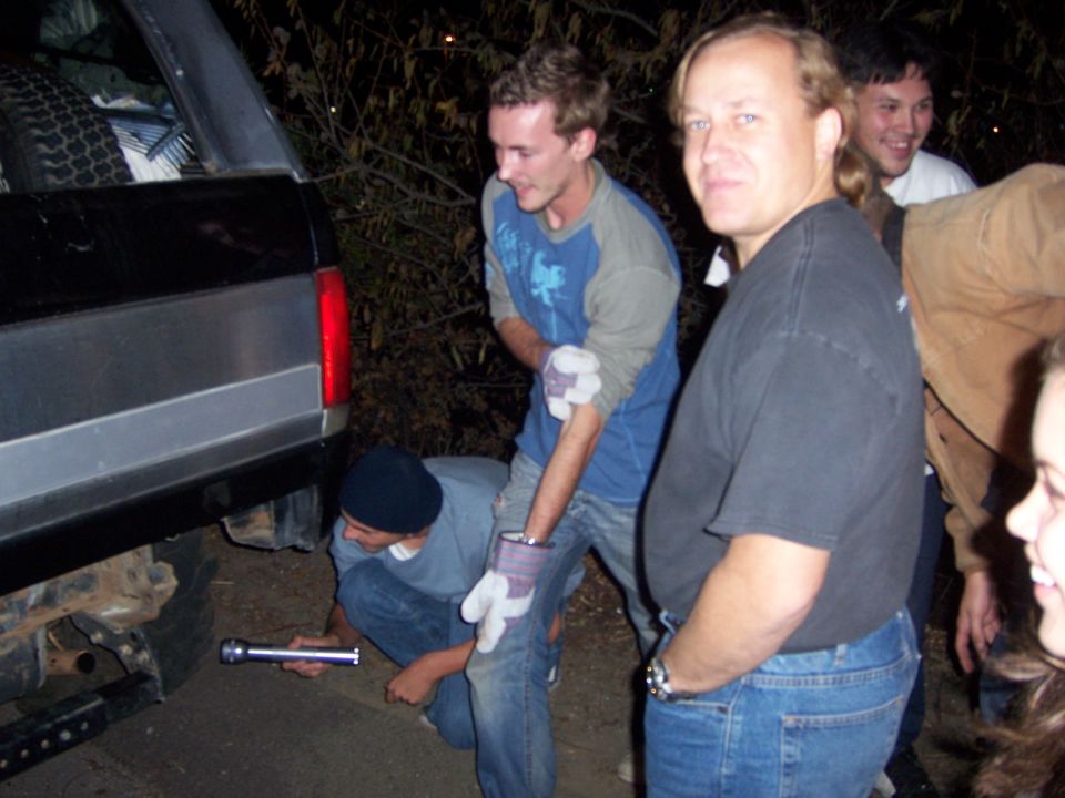 1991 Ford Bronco rear bumper with a spare tire visible inside. People are working on it