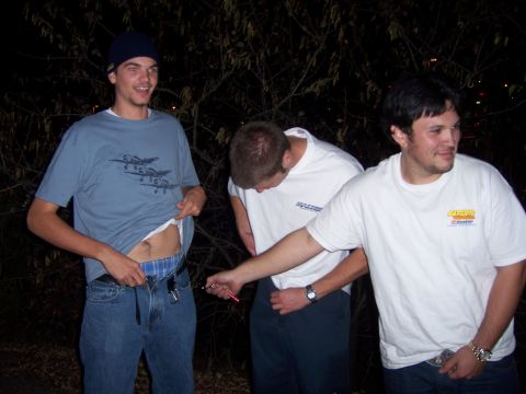 1991 Ford Bronco - Three young men are gathered outdoors at night, with one lifting his shirt to reveal his midriff.