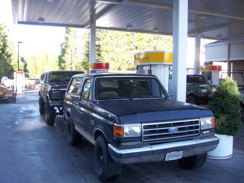 1991 Ford Bronco - Two Ford Broncos are seen at a gas station, with one in the foreground and another behind it.