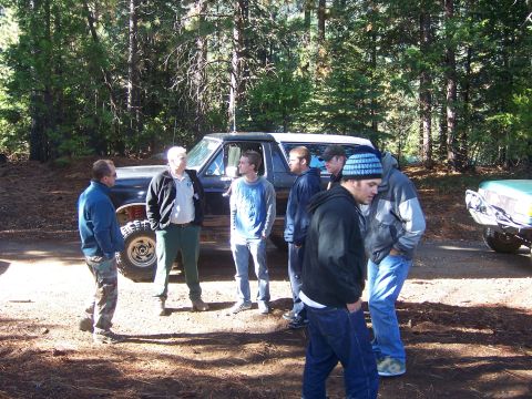 1991 Ford Bronco - A group of men gather around a classic Ford Bronco in a wooded area.