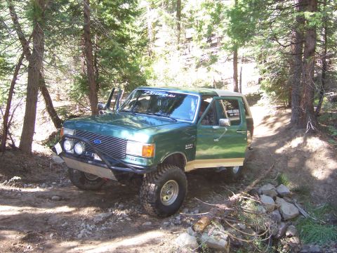 1991 Ford Bronco - This modified Ford Bronco is navigating a wooded trail with its doors open.