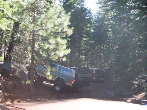 1991 Ford Bronco - A green 1992 Ford Bronco is parked on a dirt hill, with two other vehicles behind it in a wooded area.