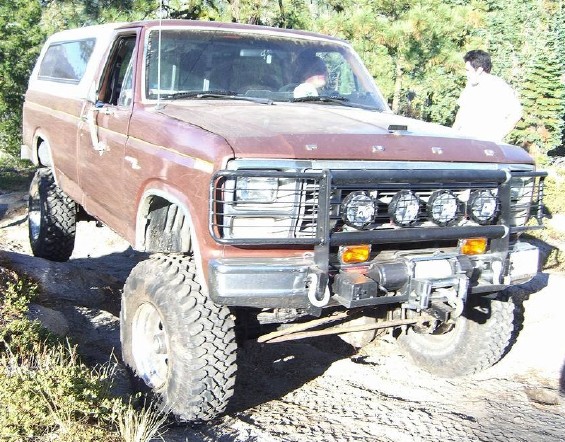 Lifted maroon Ford Bronco with brush guard, light bar and winch on trail