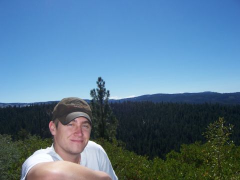 1991 Ford Bronco - A man poses for a photo with a vast expanse of trees and mountains under a clear blue sky.