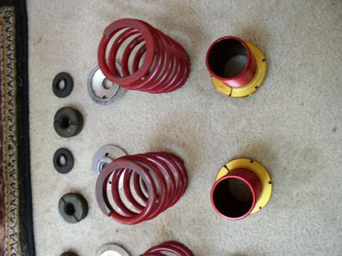 1994 Ford Probe - Various suspension components, including red coil springs and adjustable perches, are laid out on a carpeted surface.