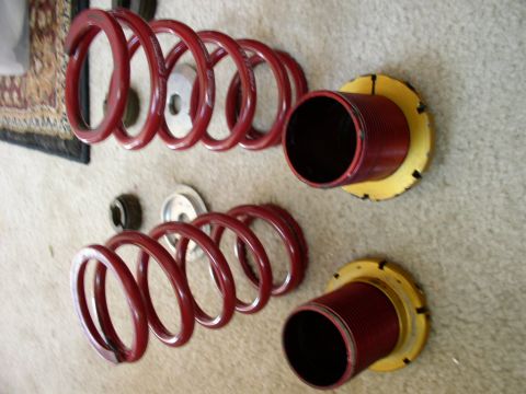 1994 Ford Probe - Pair of red coilover suspension assemblies laid out on a carpeted surface.