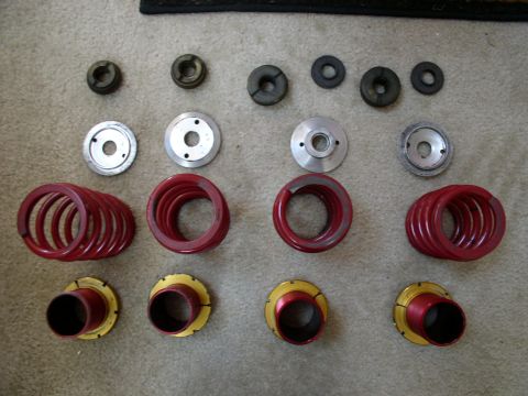 1994 Ford Probe - Various suspension components, including red coil springs and metal mounts, are arranged on a carpeted surface.
