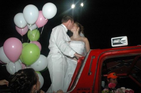 1979 Ford Bronco - A wedding couple shares a kiss next to a red pickup truck decorated with balloons and a Confederate flag.