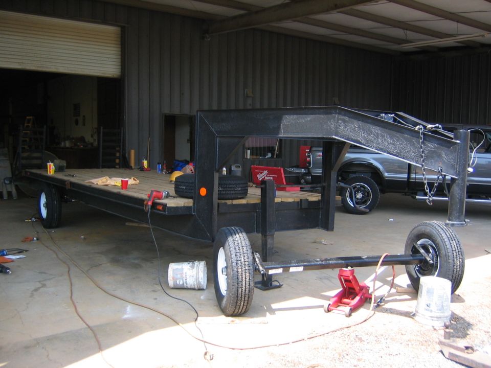 2005 Ford F-250 pickup truck parked behind a gooseneck trailer in a workshop