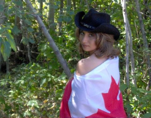1989 Ford Bronco - Outdoor portrait of a person wearing a black cowboy hat and wrapped in a Canadian maple-leaf flag, standing among green brush and saplings.…
