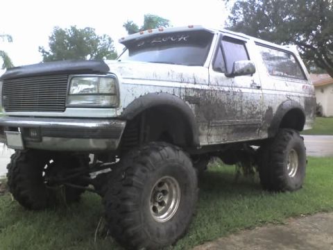 1995 Ford Bronco - Mud-covered 1995 Ford Bronco sits high on lifted suspension and oversized tires.