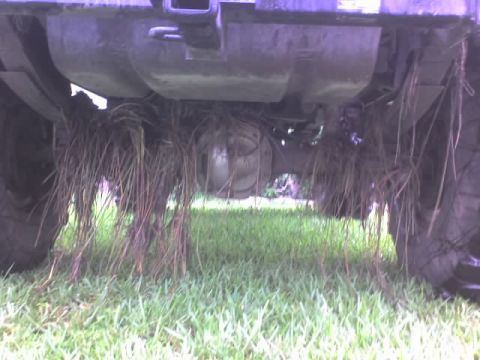 1995 Ford Bronco - Grass and debris are caught on the rear axle and suspension of an off-road vehicle.