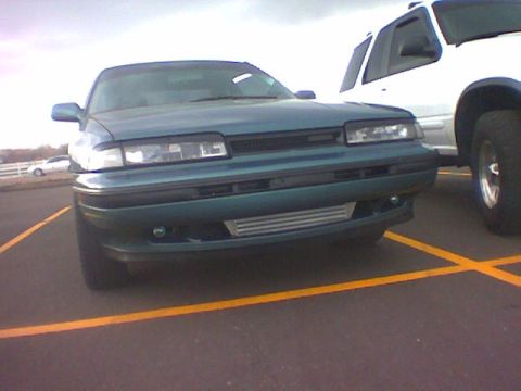 2001 Pontiac Trans Am - A teal sedan with an aftermarket intercooler is parked in a lot next to a white SUV.
