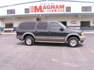 2001 Ford Excursion - A dark green Ford Excursion SUV is parked in front of a building with a "Magnum Truck & Auto" sign.