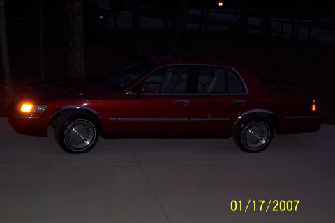 1995 Mercury Grand Marquis - Side view of a red 1995 Mercury Grand Marquis sedan parked outdoors at night.