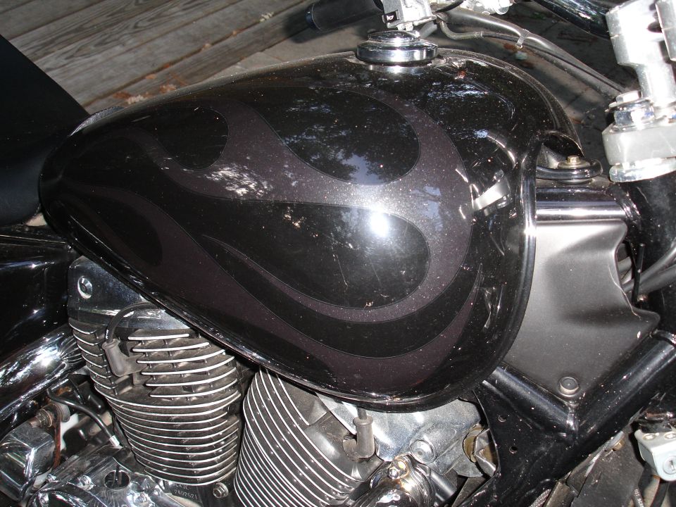 Black motorcycle fuel tank with ghost flames over a chrome V-twin engine