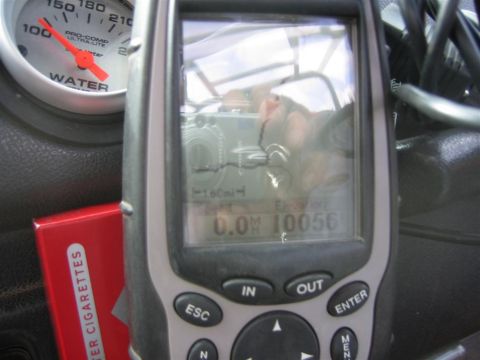 1987 Suzuki Samurai - A close-up shot of a vehicle's interior reveals a GPS device and a water temperature gauge, with a pack of cigarettes visible.