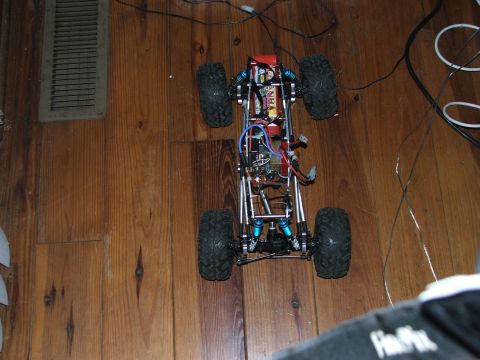 1996 Ford Bronco - The chassis of a remote control rock crawler sits on a wooden floor, showing its internal components.