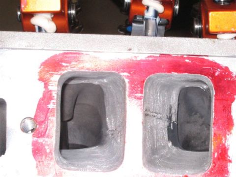 1995 Ford Bronco - Close-up of an engine cylinder head, showing intake ports and red sealant application.