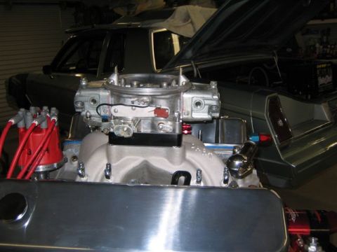 1995 Ford Bronco - A V8 engine is in the foreground, with a car's interior and open trunk in the background.