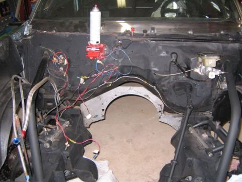 1995 Ford Bronco - The engine bay of a vehicle is shown with exposed wiring and components.