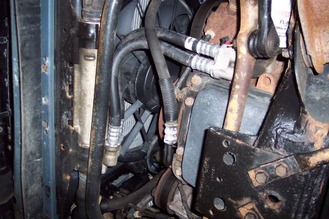 2001 Ford Crown Victoria - Underside view of engine bay components, including hoses and a fan, with visible rust.