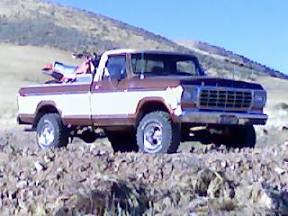 1979 Ford F-150 - A 1979 Ford F-150 pickup truck with a dirt bike loaded in the bed sits on a rocky incline under a clear blue sky.
