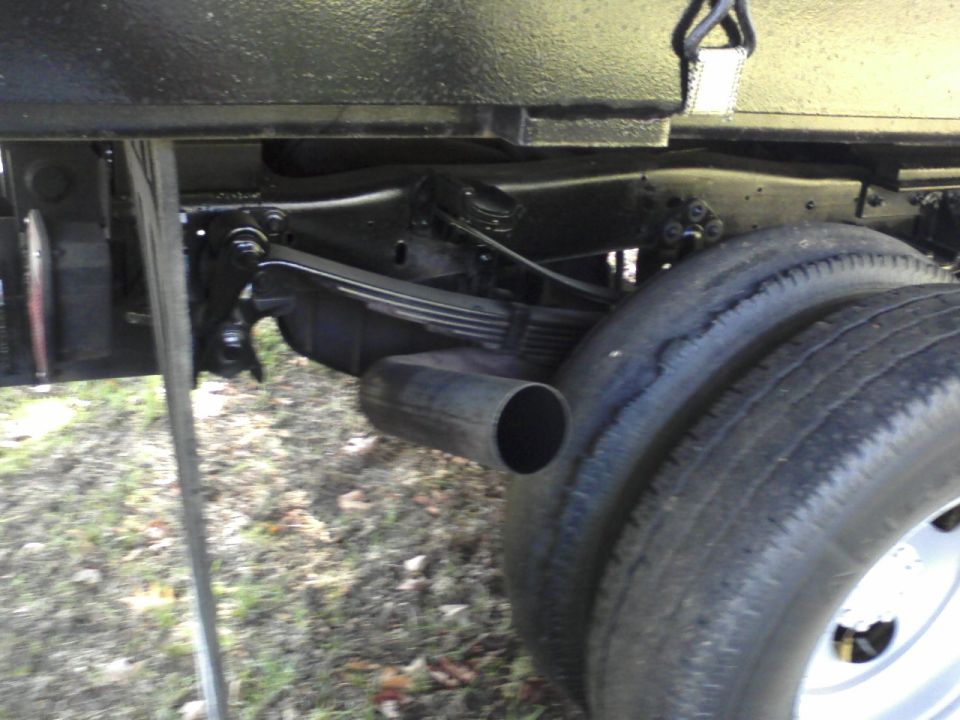 Undercarriage with multi-leaf spring, large exhaust outlet, and tall tire on a black-undercoated frame