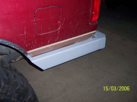 1995 Ford Bronco - A light gray aftermarket step is installed on the rear bumper of a red vehicle.