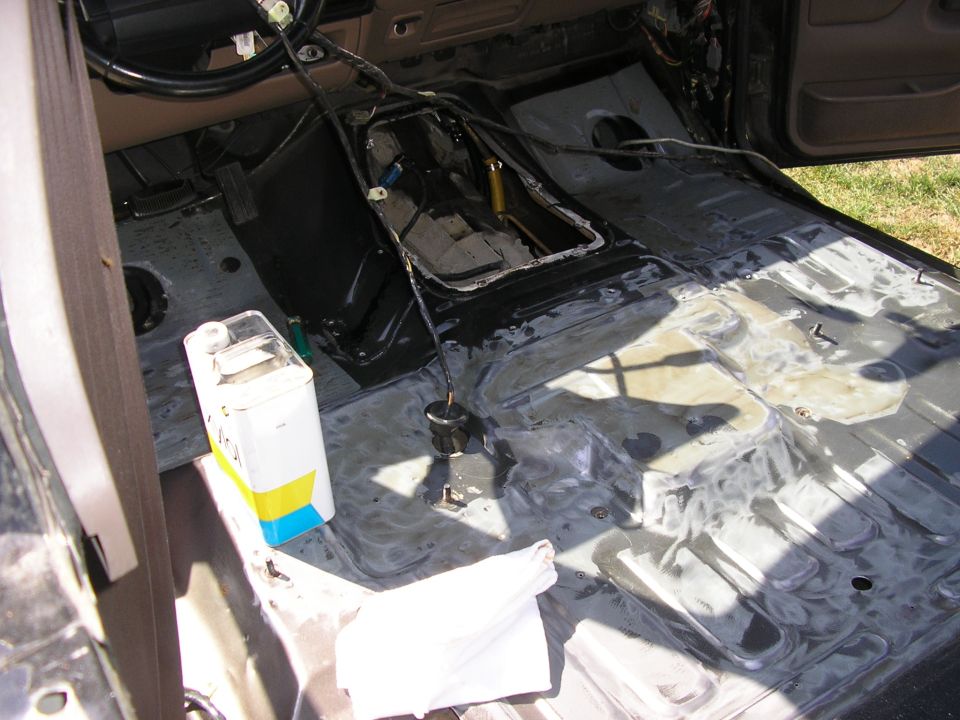 Bare stamped steel floor pan of a stripped truck interior with shifter exposed and solvent can