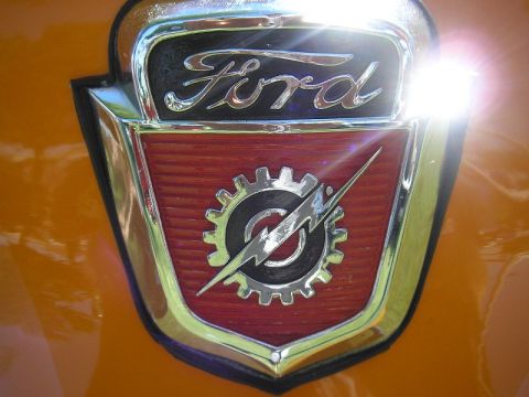 1993 Ford Bronco - A close-up of a vintage Ford emblem on an orange vehicle, indicating an earlier model year than claimed.