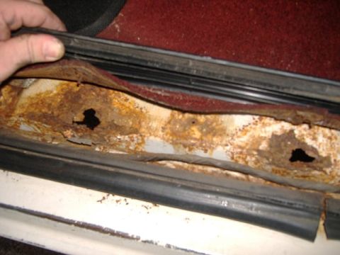 1987 Ford Bronco - Severe rust damage visible on the door sill of a vehicle.