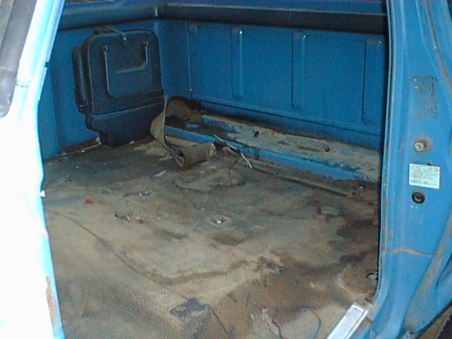 Stripped blue truck cab interior showing bare floor pan with seats and carpet removed