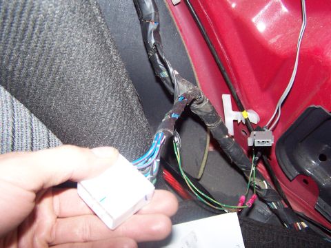 1994 Ford Probe - Close-up of a car's interior wiring harness with a hand holding a connector.
