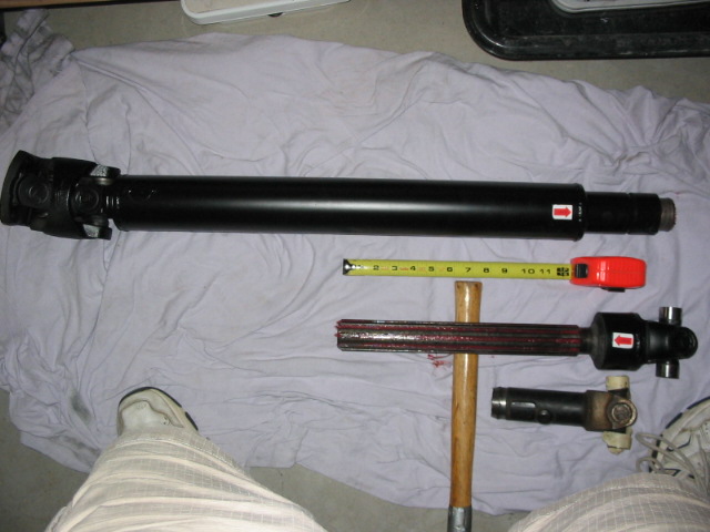 Black driveshaft and U-joint parts with tape measure on a purple sheet