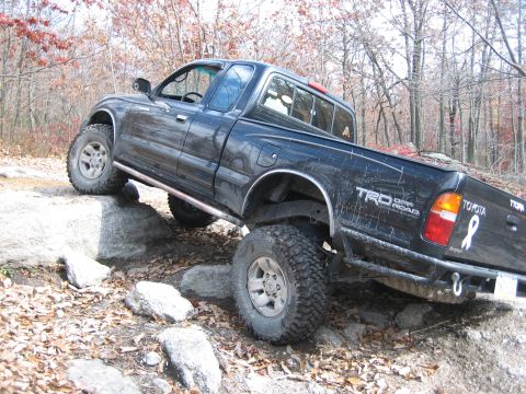 1990 Ford Bronco - Toyota pickup truck with TRD Off Road package is shown off-roading on a rocky trail.