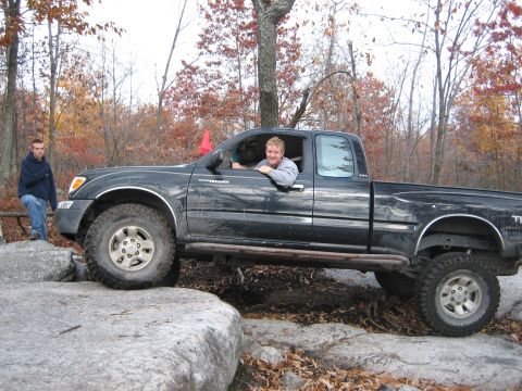 1990 Ford Bronco - A black Toyota Tacoma navigates a rocky trail with a driver and passenger.
