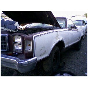 1973 Ford Ranchero - A white pickup truck sits in a junkyard with its hood up, showing disassembled parts.