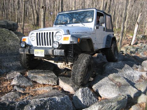1990 Ford Bronco - This Jeep Wrangler navigates a challenging rocky trail, demonstrating its off-road capabilities.