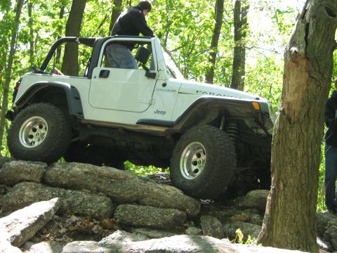 1990 Ford Bronco - This Jeep Wrangler is navigating a rocky obstacle course in a wooded area.