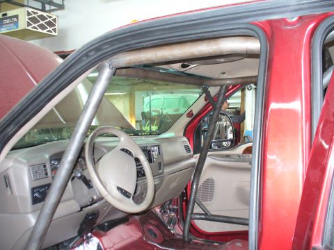 1978 Ford Bronco - The interior of a red truck shows a custom roll cage installed around the cabin.