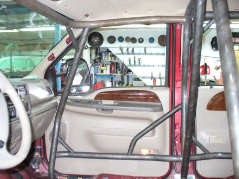 1978 Ford Bronco - Custom roll cage installed inside a truck cab, with a workshop visible through the window.