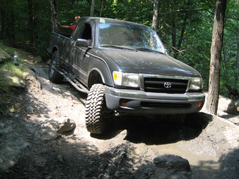 1990 Ford Bronco - A dark pickup truck with aggressive tires maneuvers through a challenging off-road course.