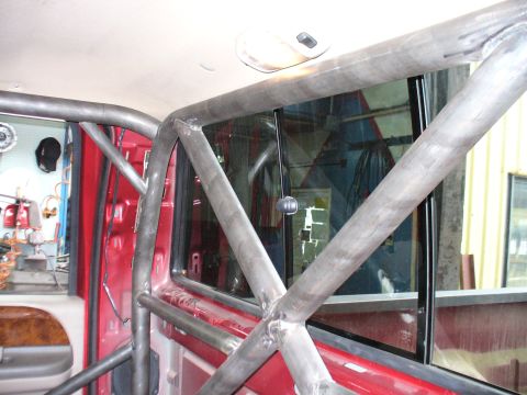 1978 Ford Bronco - The interior of a red vehicle is visible, fitted with a custom metal roll cage.