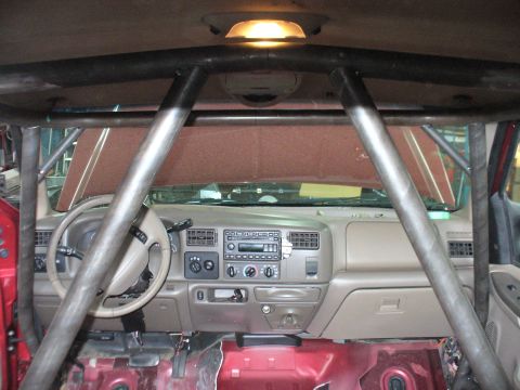 1978 Ford Bronco - The interior of a vehicle is visible, a prominent roll cage structure and the dashboard.